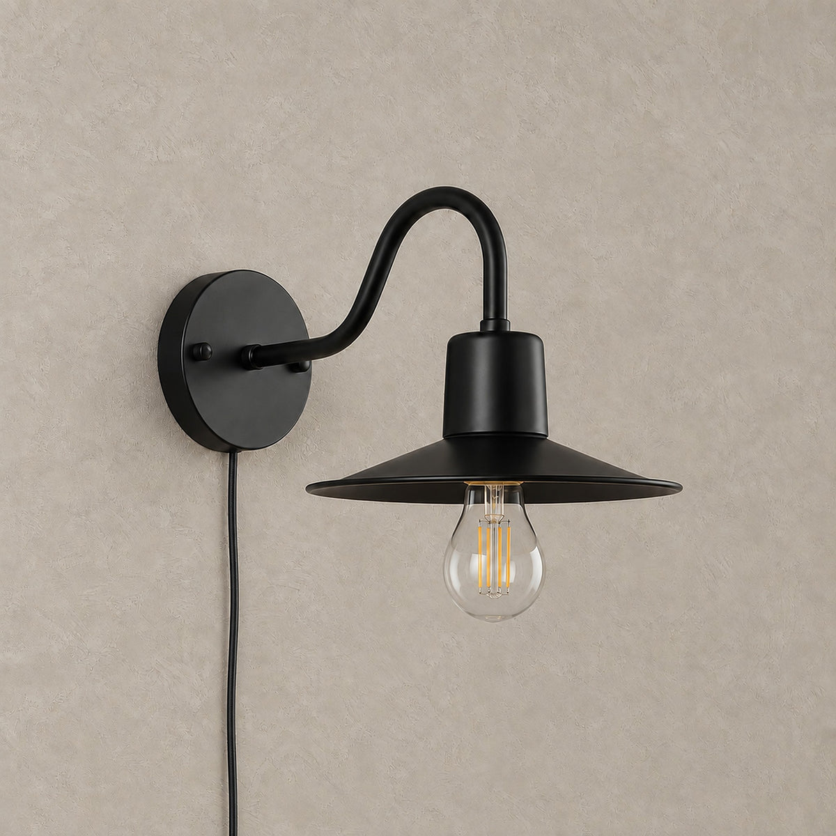 Tarelio black plug in wall sconce unlit, a clear vintage style bulb under a shallow conical metal shade