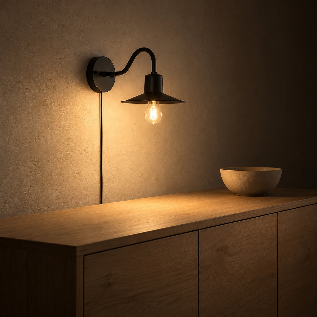 Tarelio black wall sconce lighting the plaster wall of a dining room at night