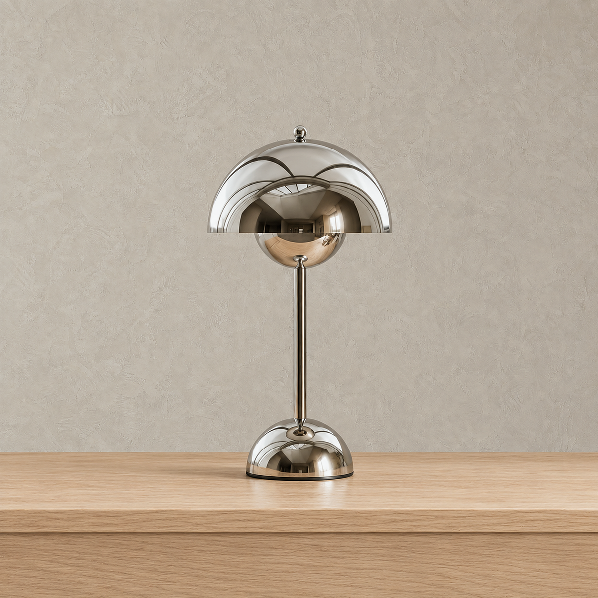Temalor silver rechargeable table lamp in reflective stainless steel, shown unlit against greige plaster