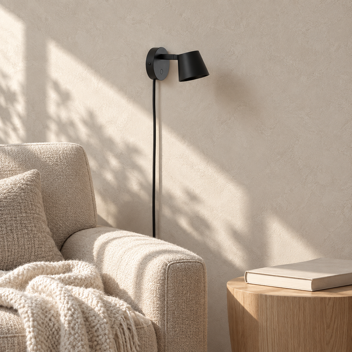 Tisello black adjustable wall sconce unlit beside a sunlit chair in a library alcove