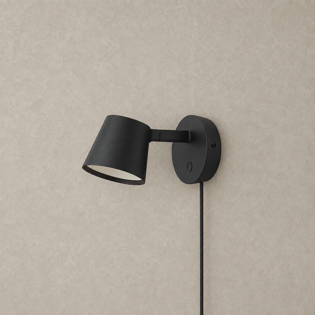 Tisello black adjustable wall sconce with its tapered shade unlit on a plain backdrop
