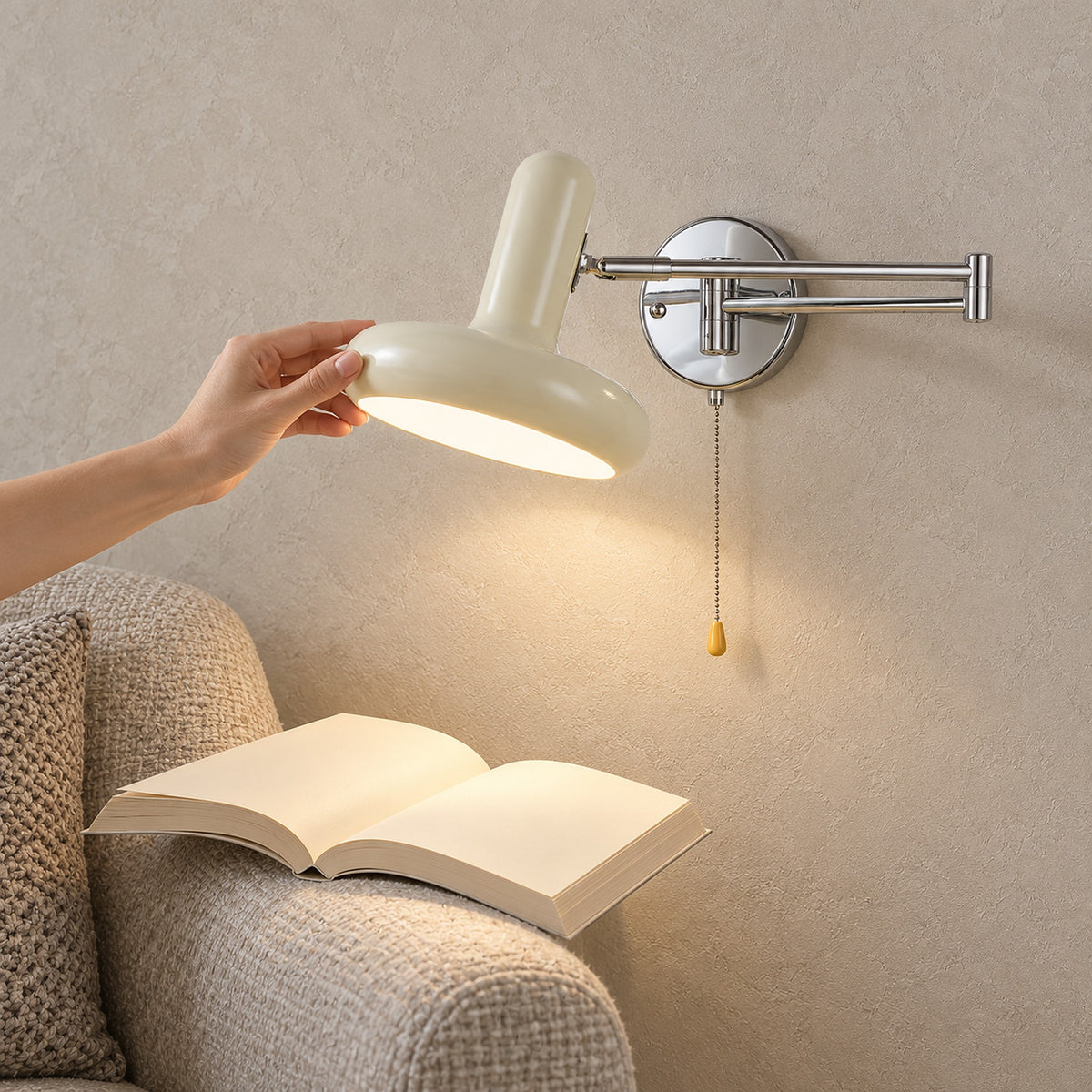 Tivenola cream wall lamp with its rotatable shade turned by hand in a living room reading corner
