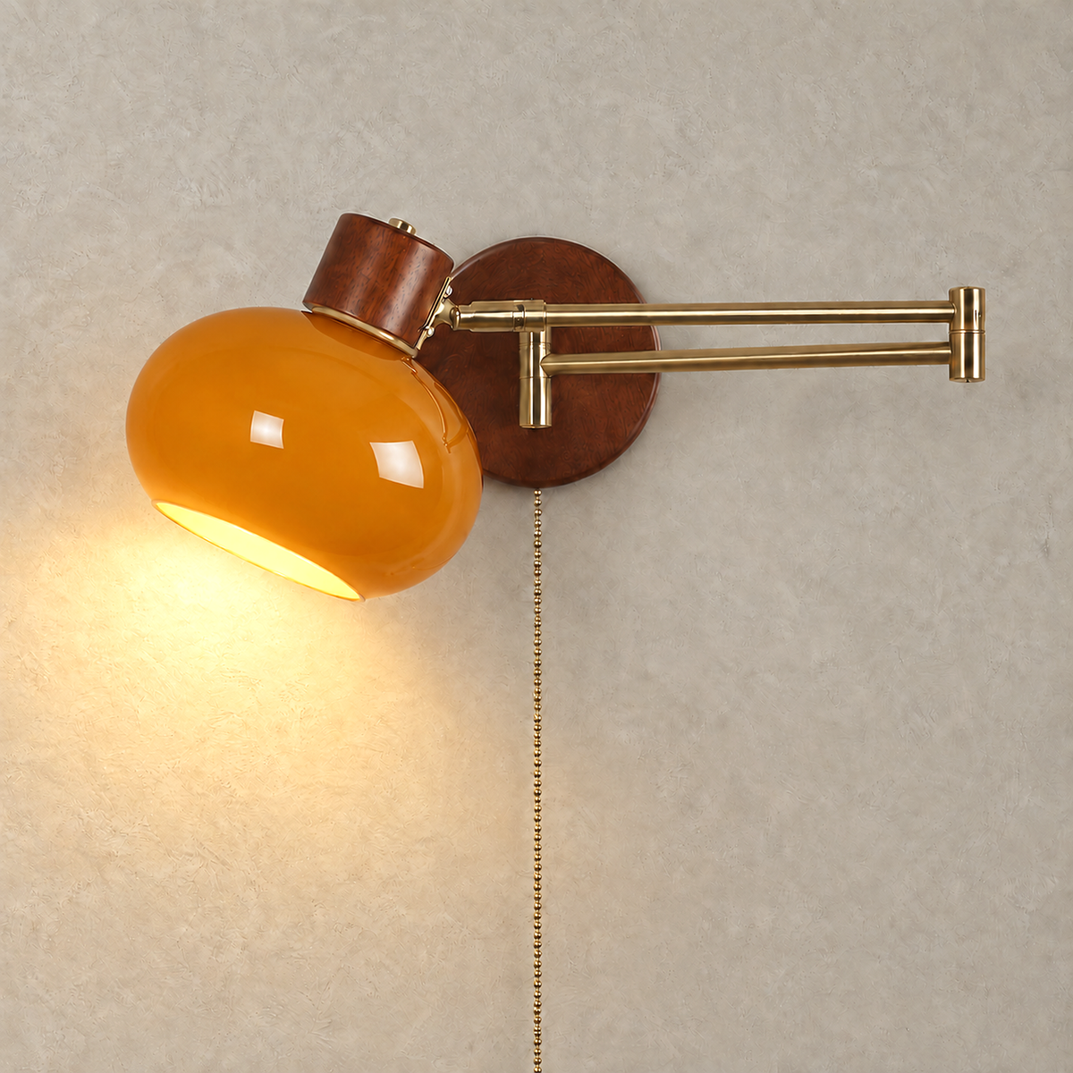 Tolvaren amber wall sconce switched on, its glass shade lighting a greige plaster wall
