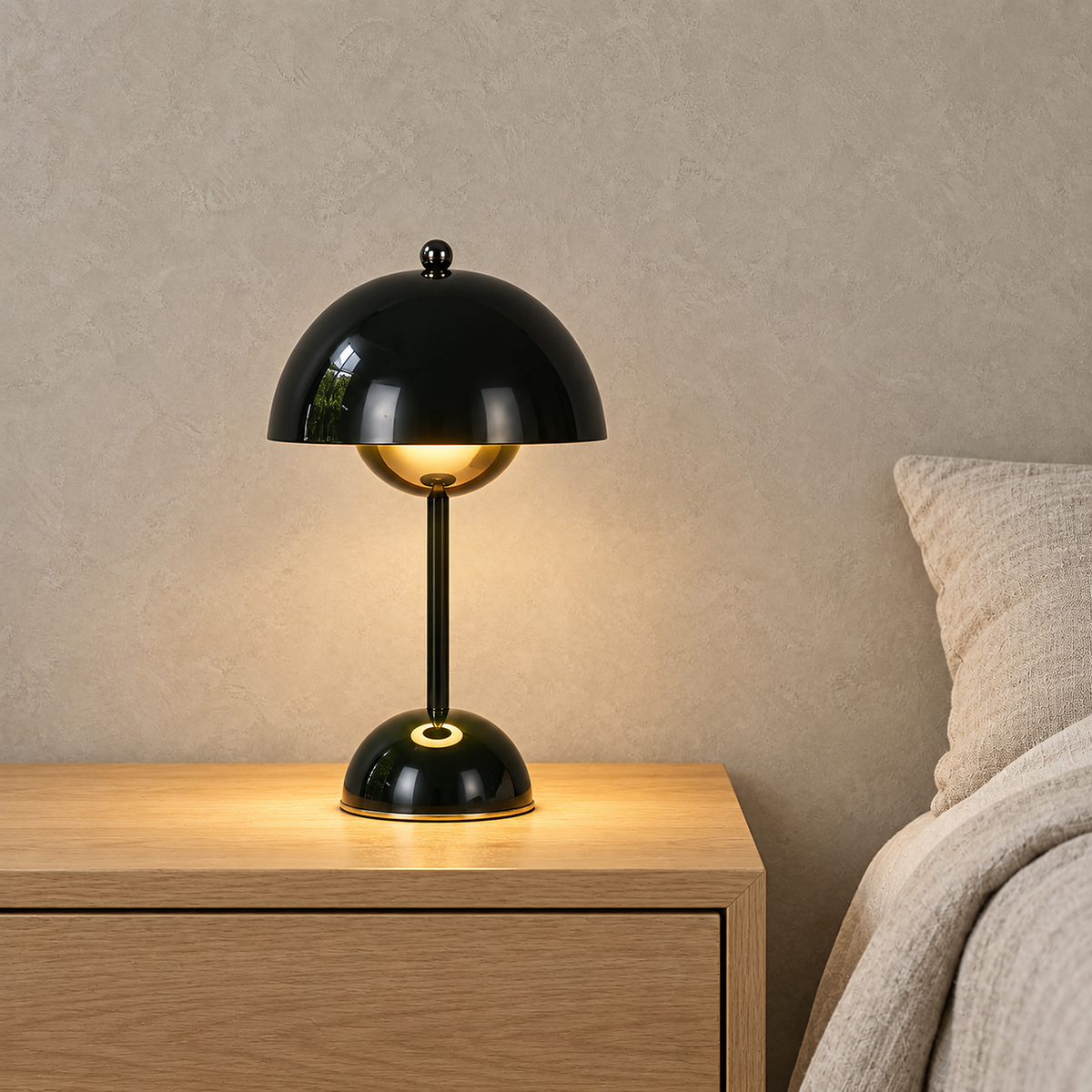 Varimel black bedside lamp glowing beside oatmeal bedding in a bright upstairs bedroom