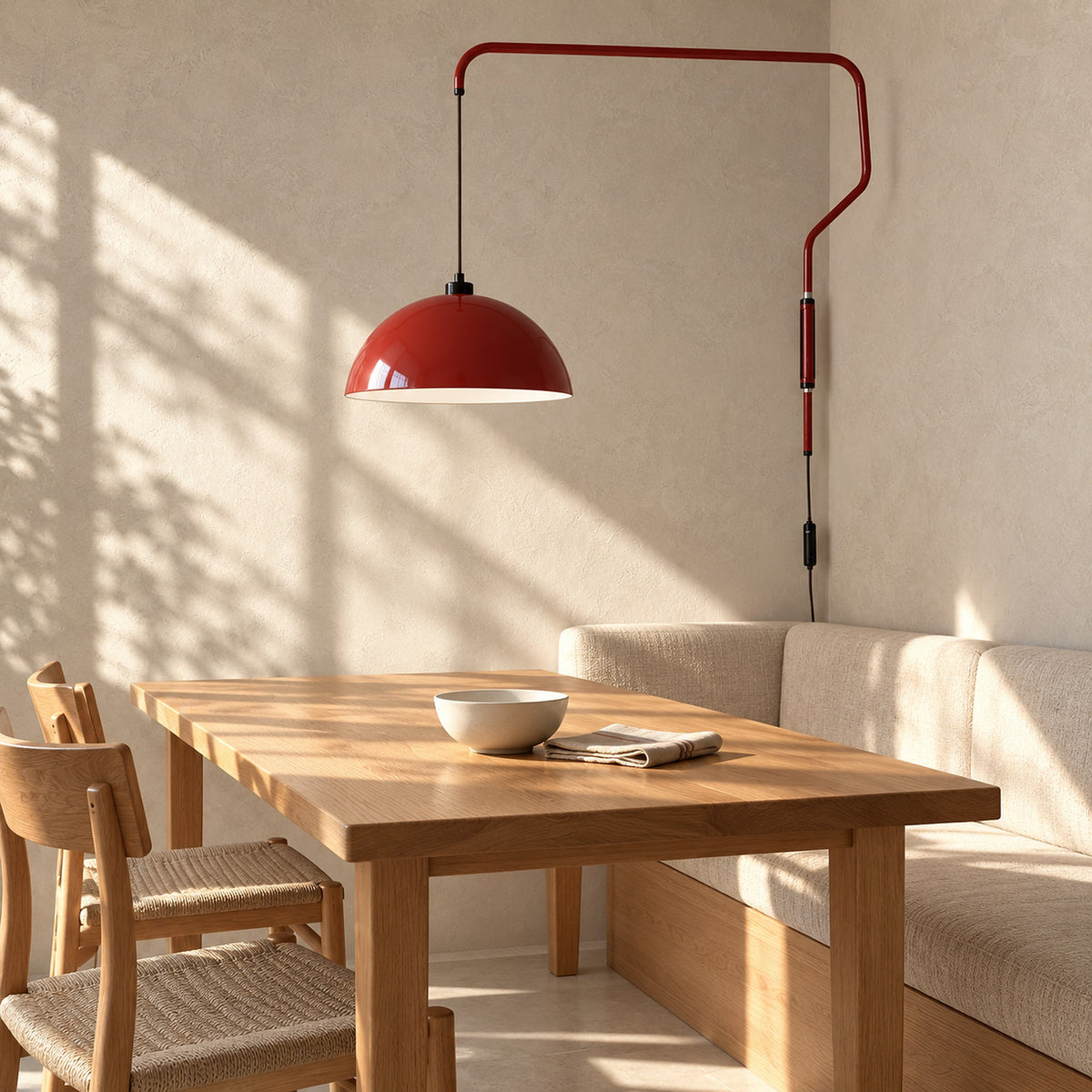 Velisano dark red plug in wall light hanging above a sunlit breakfast table, switched off