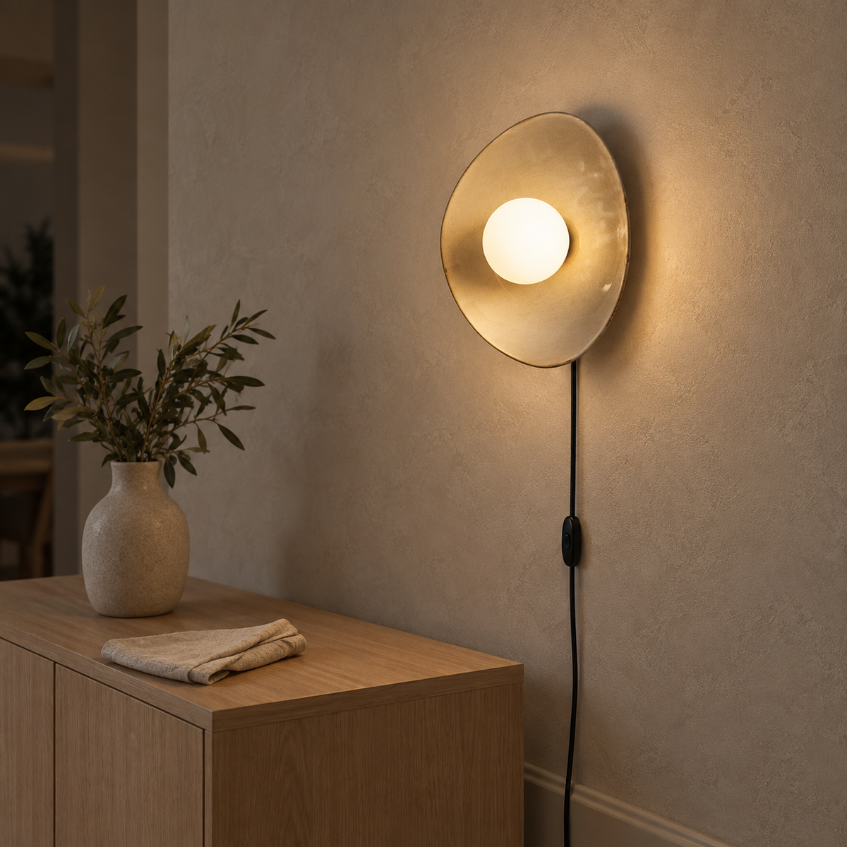 Venalti taupe ceramic LED wall sconce lit and seen from an oblique angle in a dining room