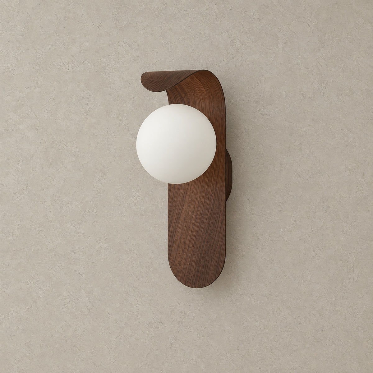 Arcelmo walnut hardwired wall sconce, unlit with its round globe and curved wood grain accent against greige plaster