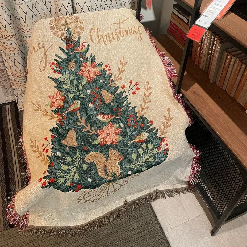 Canelvi christmas jacquard throw blanket draped over a chair, showing a decorated tree and fringed edges.