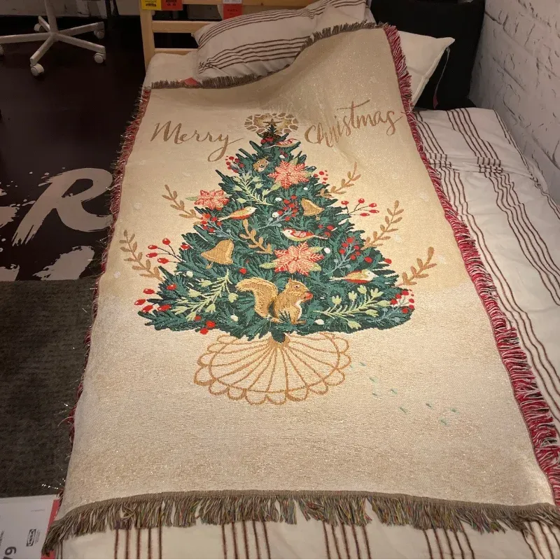 Canelvi christmas jacquard throw blanket spread across a bed, showing a Christmas tree design and fringed edges.