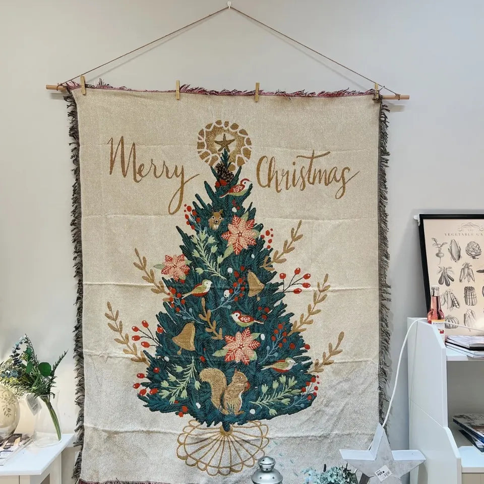 Canelvi christmas jacquard throw blanket hangs on a wall, showing a Christmas tree and Merry Christmas lettering.
