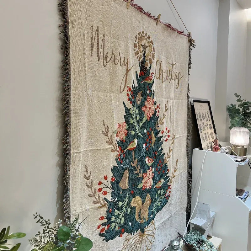 Canelvi christmas jacquard throw blanket hangs on a wall, showing a tree design, fringed edges and Merry Christmas text.