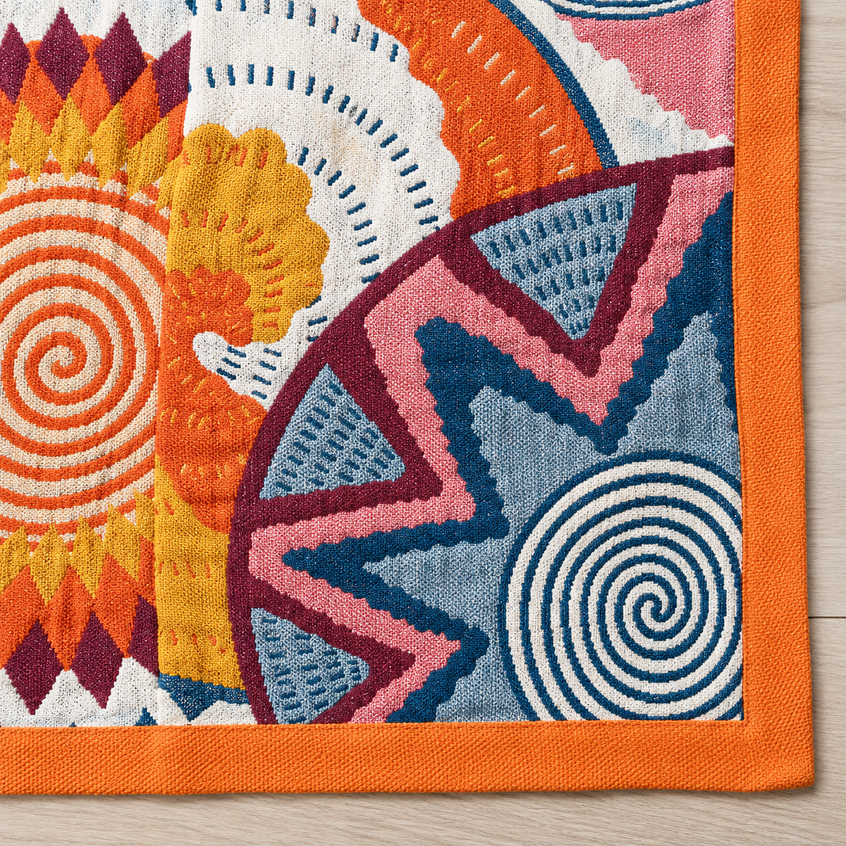 Ciranel multicolored & cotton jacquard blanket up close, a dark teal and cream spiral beside the orange border