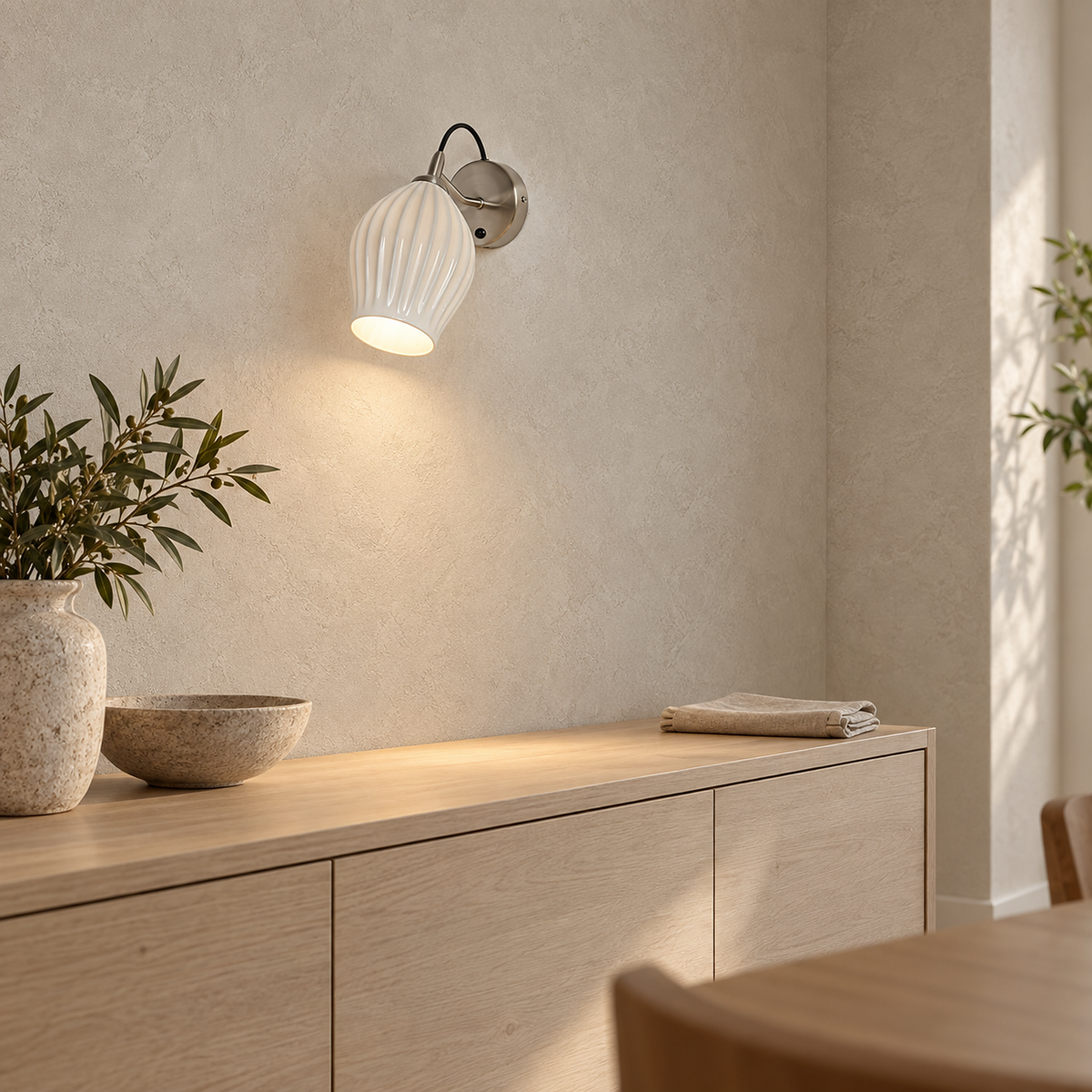 Comirel chrome wall sconce lit showing the round back plate and curved arm