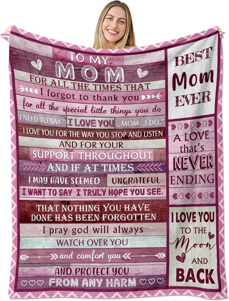 Woman holds an Elmisa mom fleece throw blanket fully open, showing pink borders, hearts and messages to Mom.
