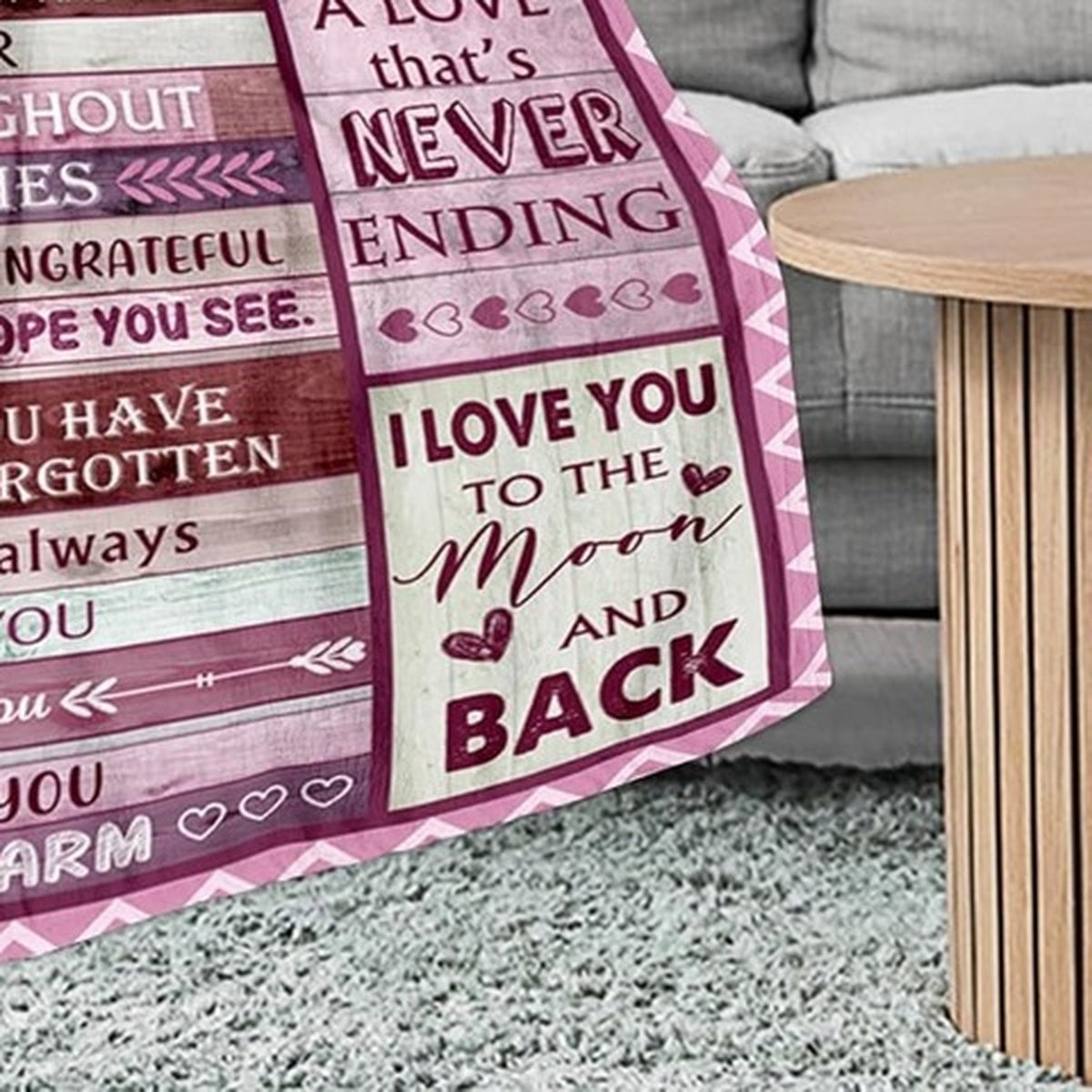 Elmisa mom fleece throw blanket draped over a gray sofa, showing pink love messages beside a round wooden table.