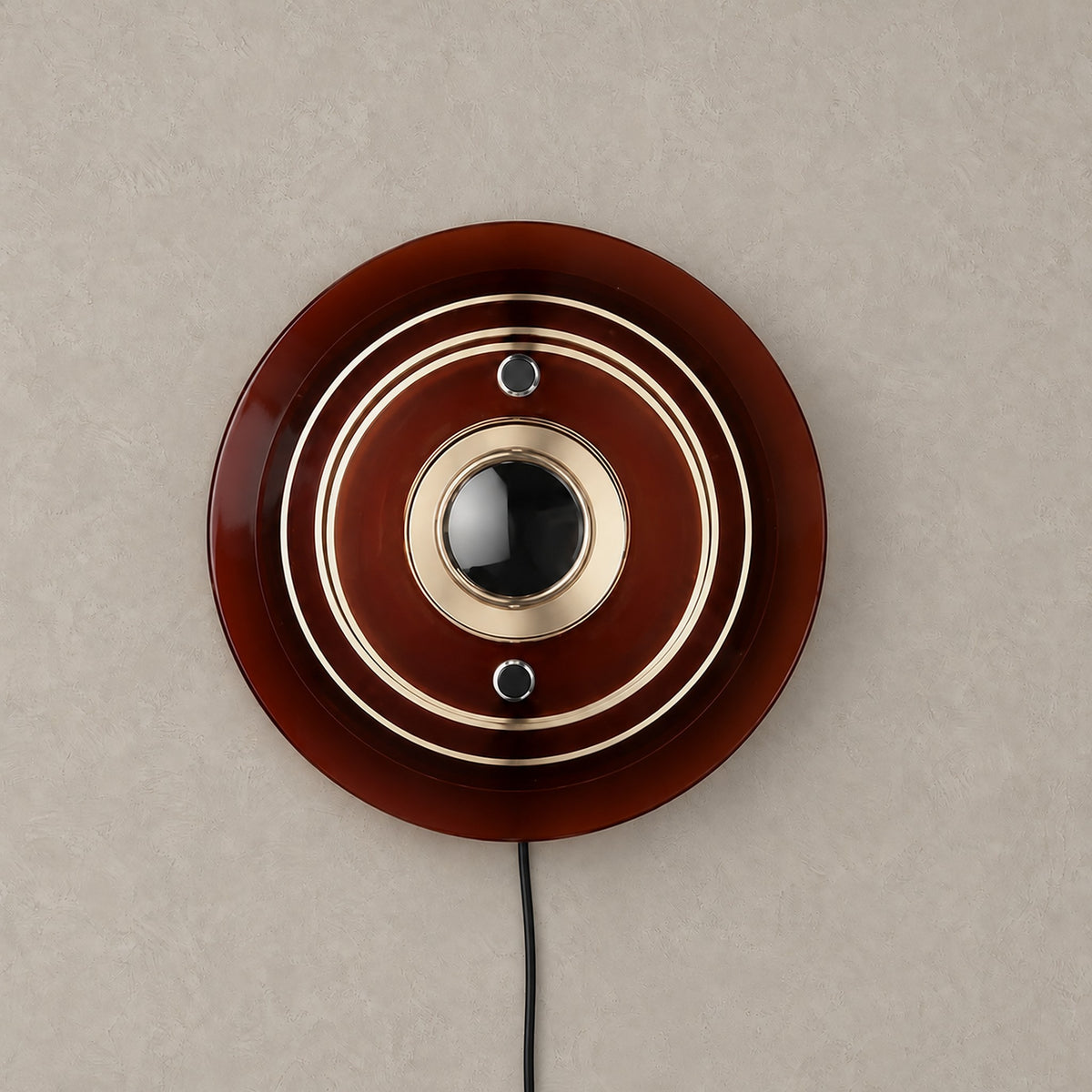 Elsarvo brown plug in wall sconce with stacked acrylic rings unlit on a plain backdrop