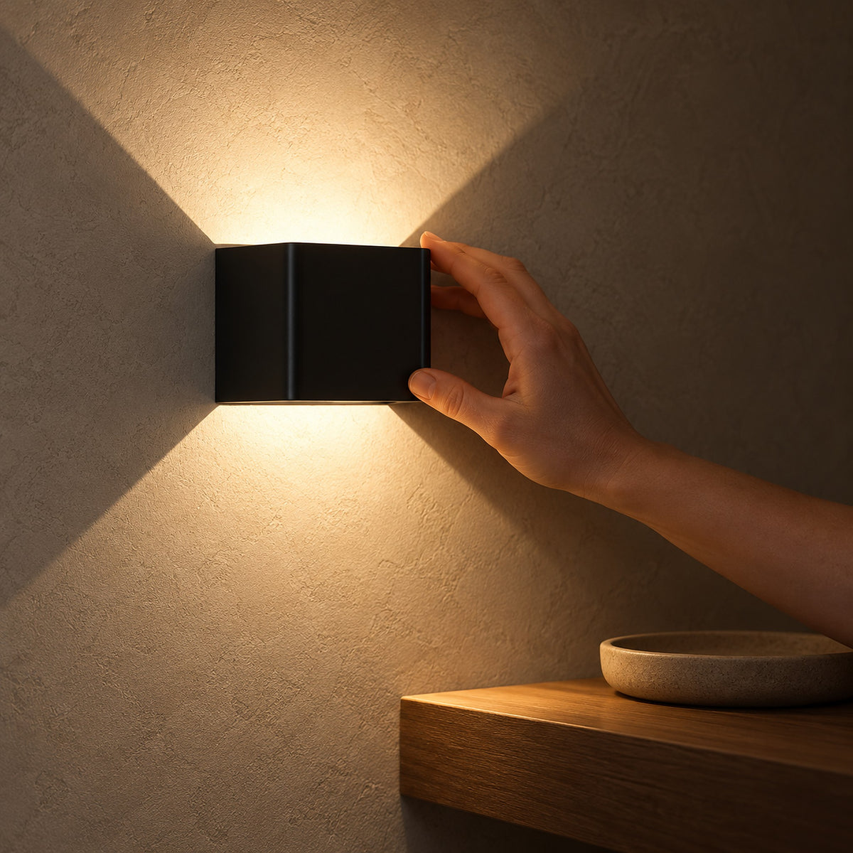 Ivelmo black cordless wall lamp directing warm light along entryway plaster at night