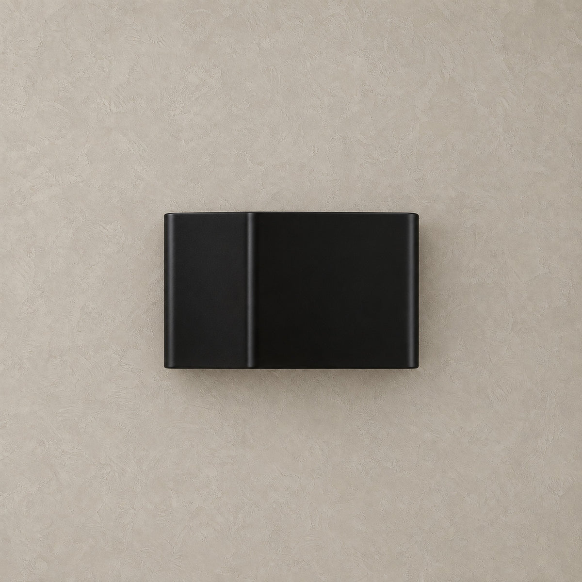 Ivelmo black rechargeable wall sconce shown unlit against a greige plaster wall