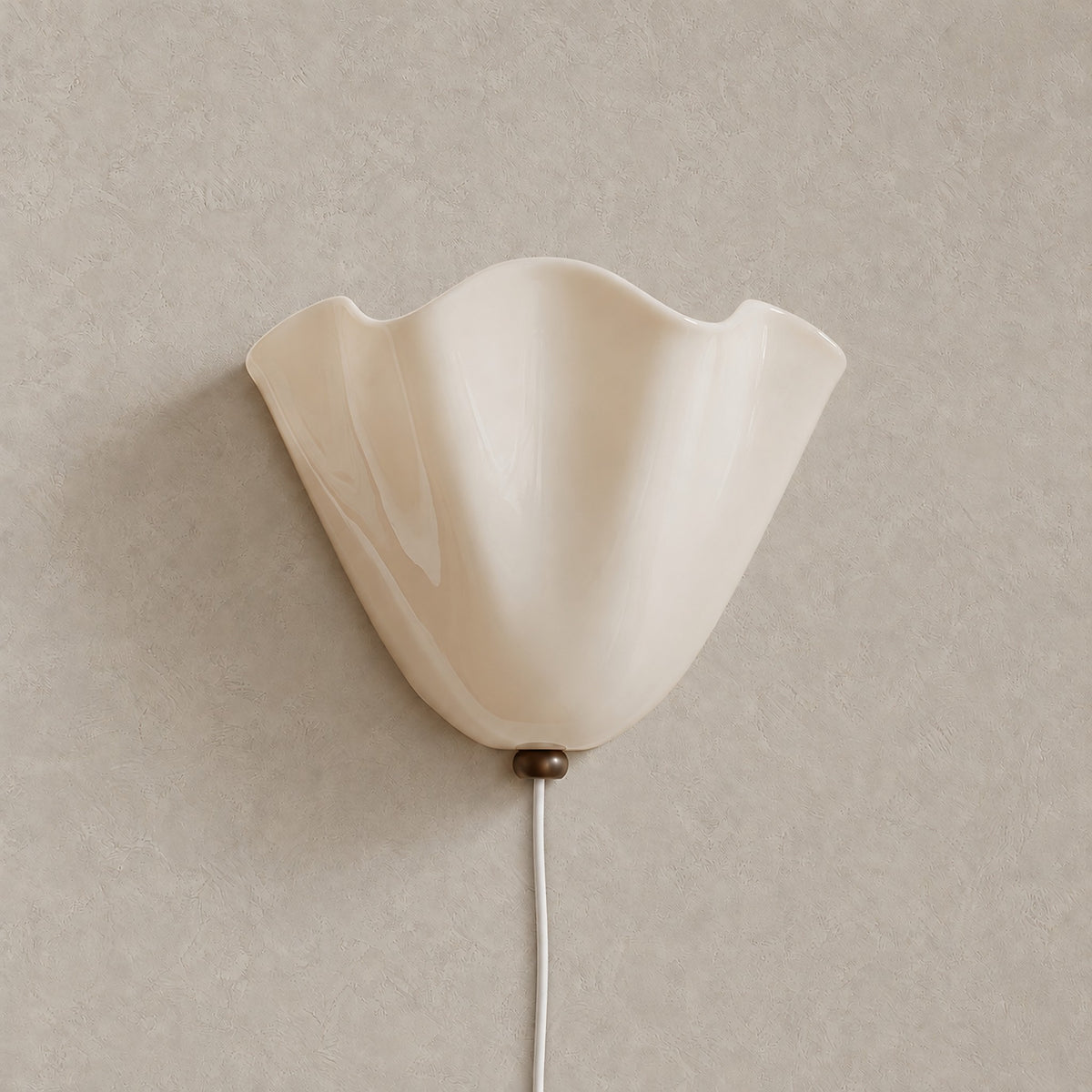 Lanorvi glass wall sconce in ivory, unlit and mounted on a greige plaster wall