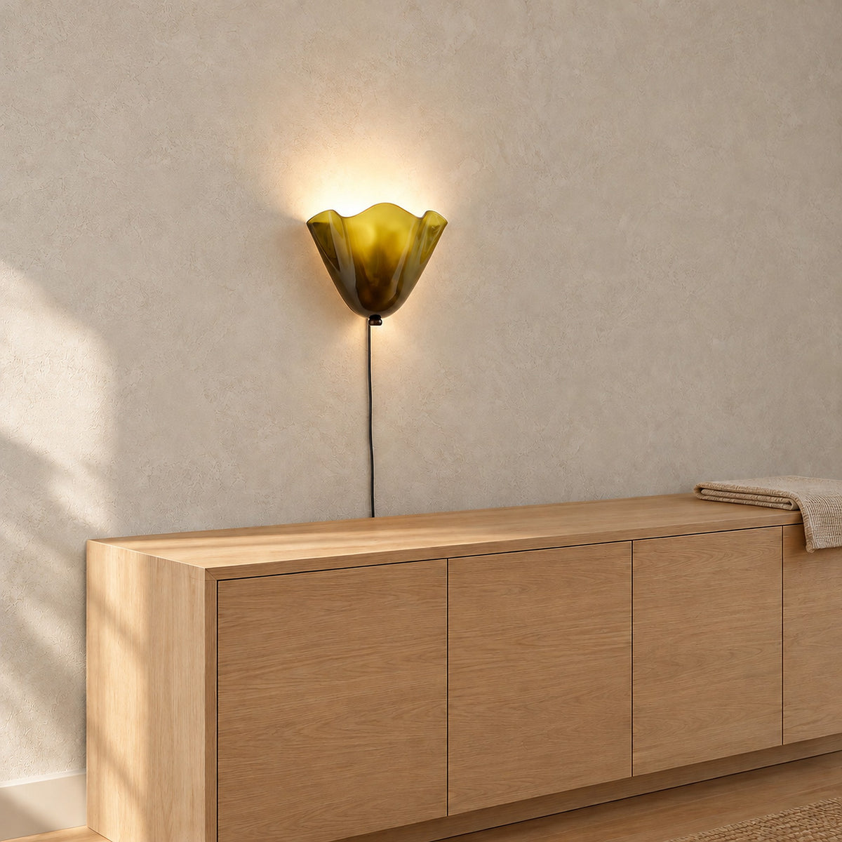 Lanorvi green glass wall sconce glowing over dining room furniture by day #color_green