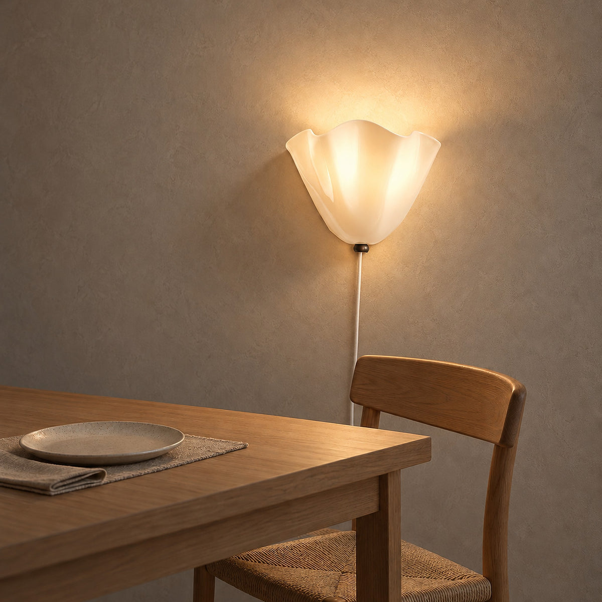 Lanorvi ivory glass wall lamp lit beside a dining table in soft midday light