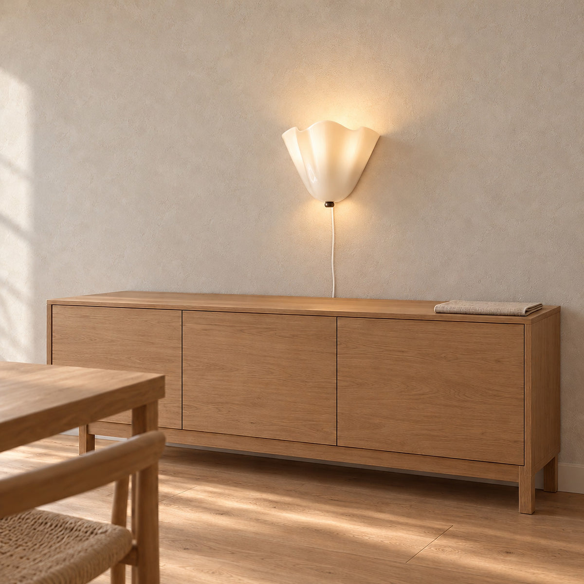 Lanorvi ivory glass wall light lit, showing the curved glass and lower fitting