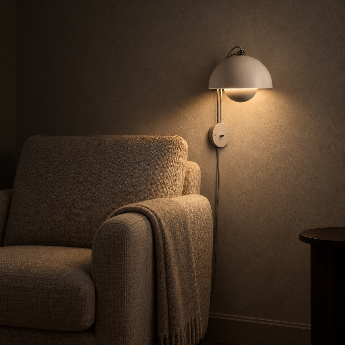 Lasorme cream wall light casting warm light beside an armchair in a reading corner at night
