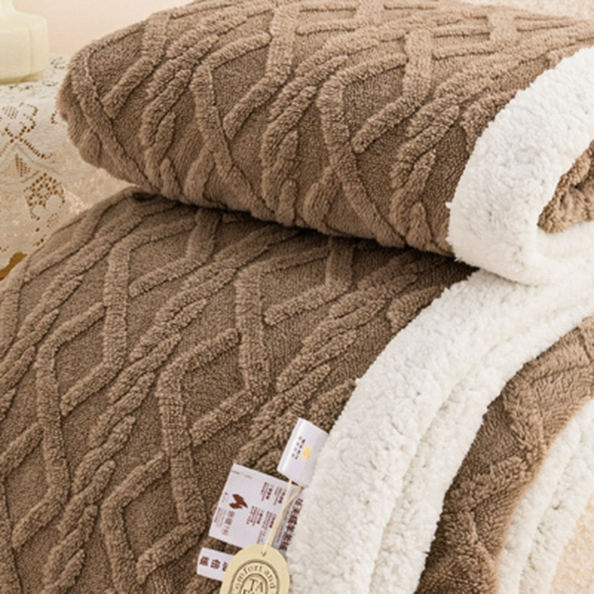 Lerivosa brown reversible fleece throw blanket with white lining, folded over a white upholstered chair