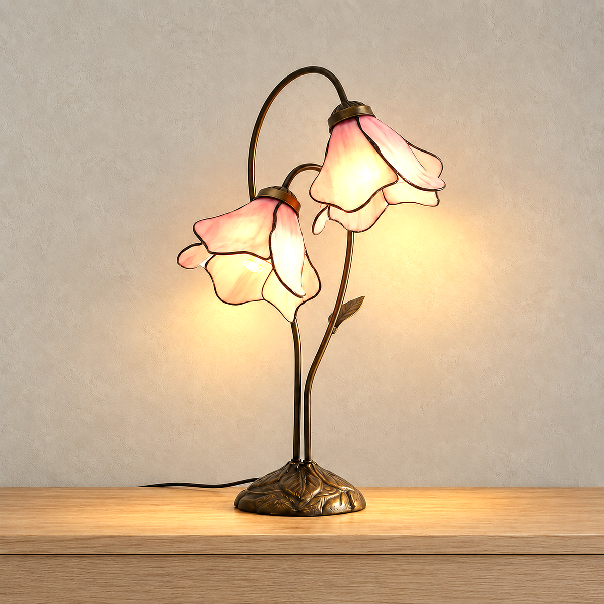 Linavor pink bedside lamp switched on, its stained glass flower petals lit from inside