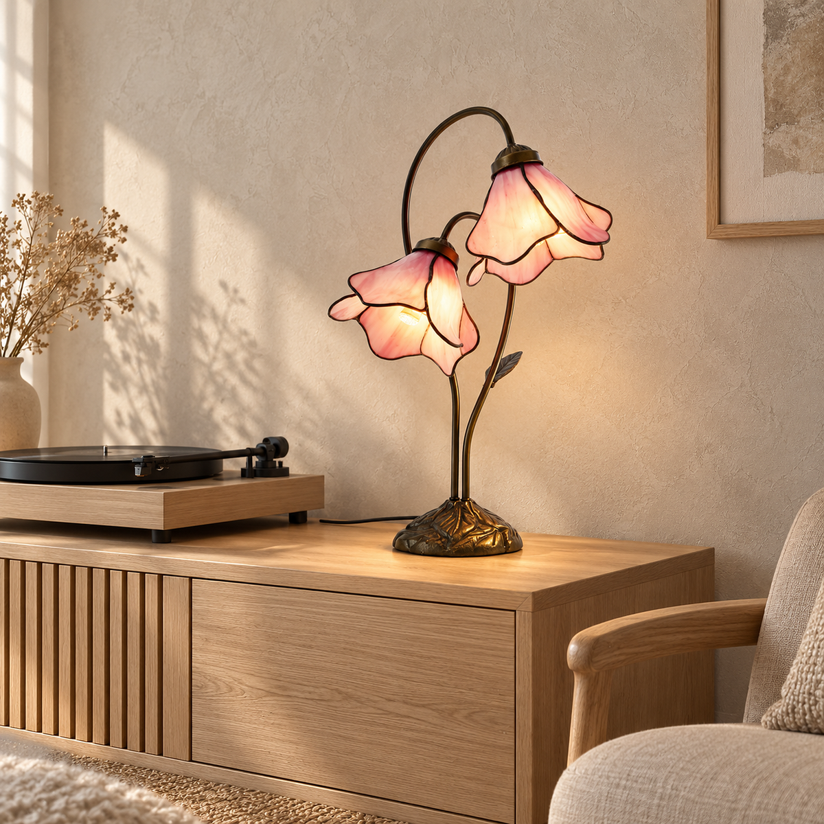 Linavor stained glass table lamp in pink, lit, showing the leaf shaped iron base and curved stems