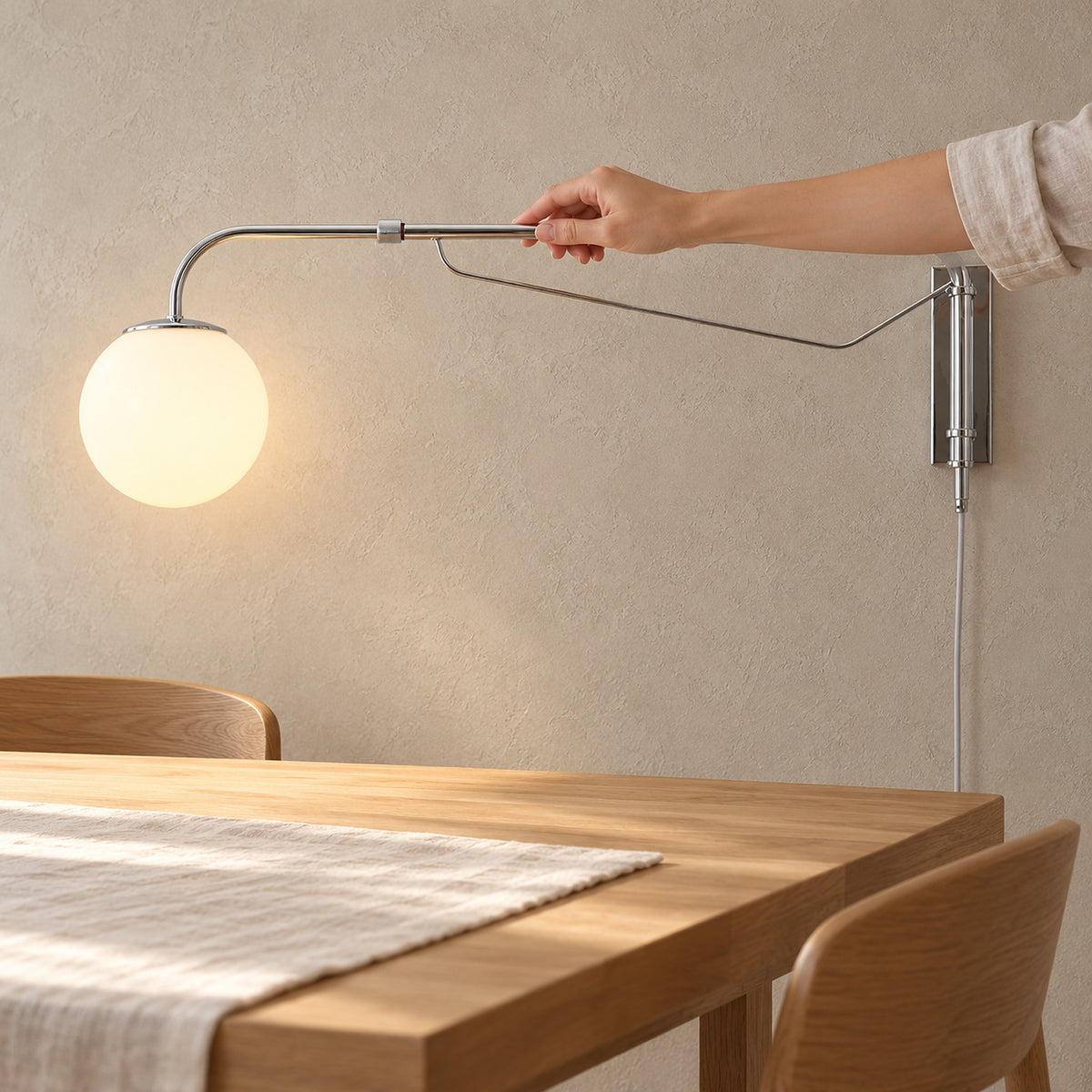 Lirelso chrome and white wall lamp, a hand adjusting the telescoping arm in a dining room craft nook