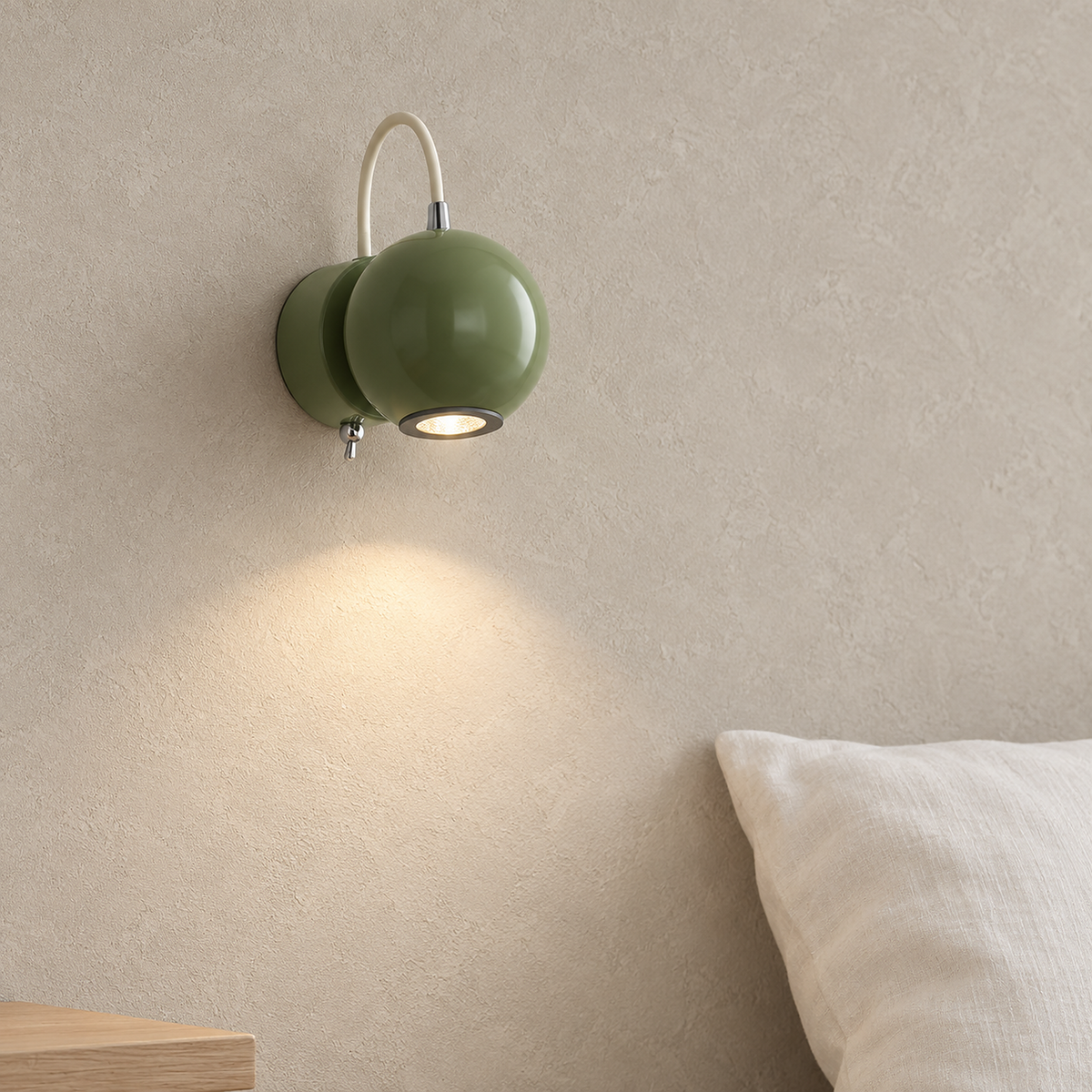 Lirema green bedside wall light glowing warm beside a pillow and a clear nightstand in a sleeping alcove