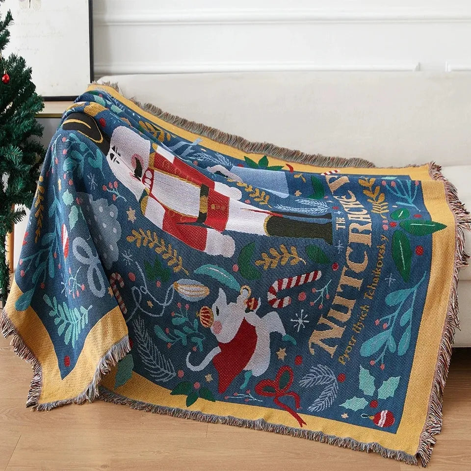 Lisorvan christmas cotton throw blanket draped over a white sofa, showing nutcracker motifs, gold border and fringe.