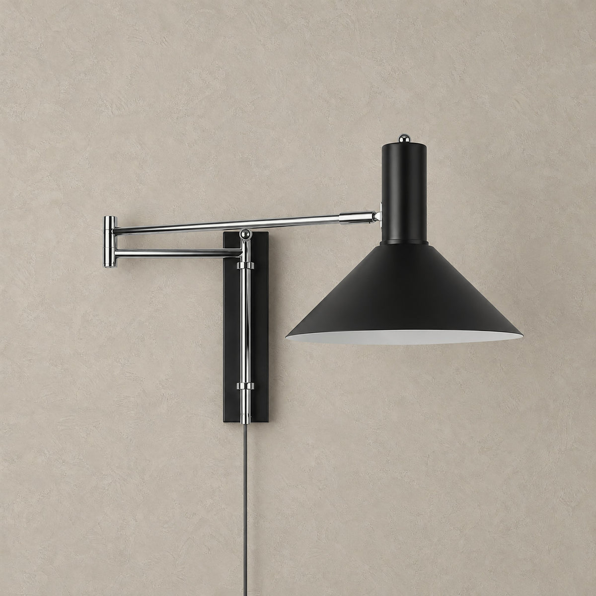 Lomaresi swing arm wall lamp in black, unlit against a greige plaster wall
