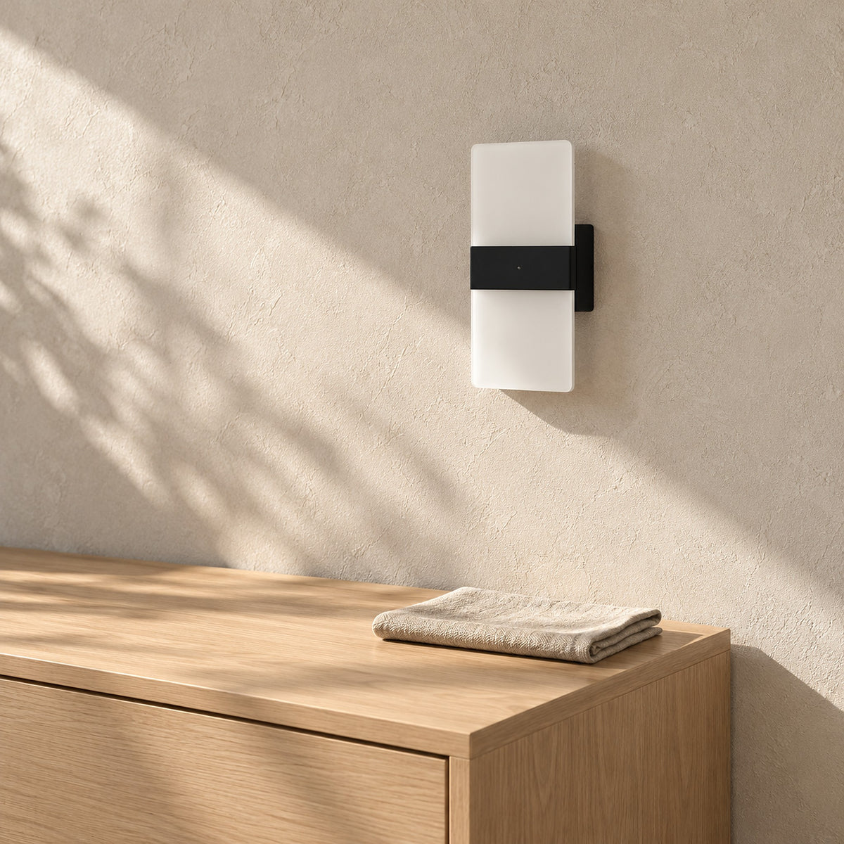 Melavor black battery operated wall sconce, unlit on a dining room wall in direct sunlight