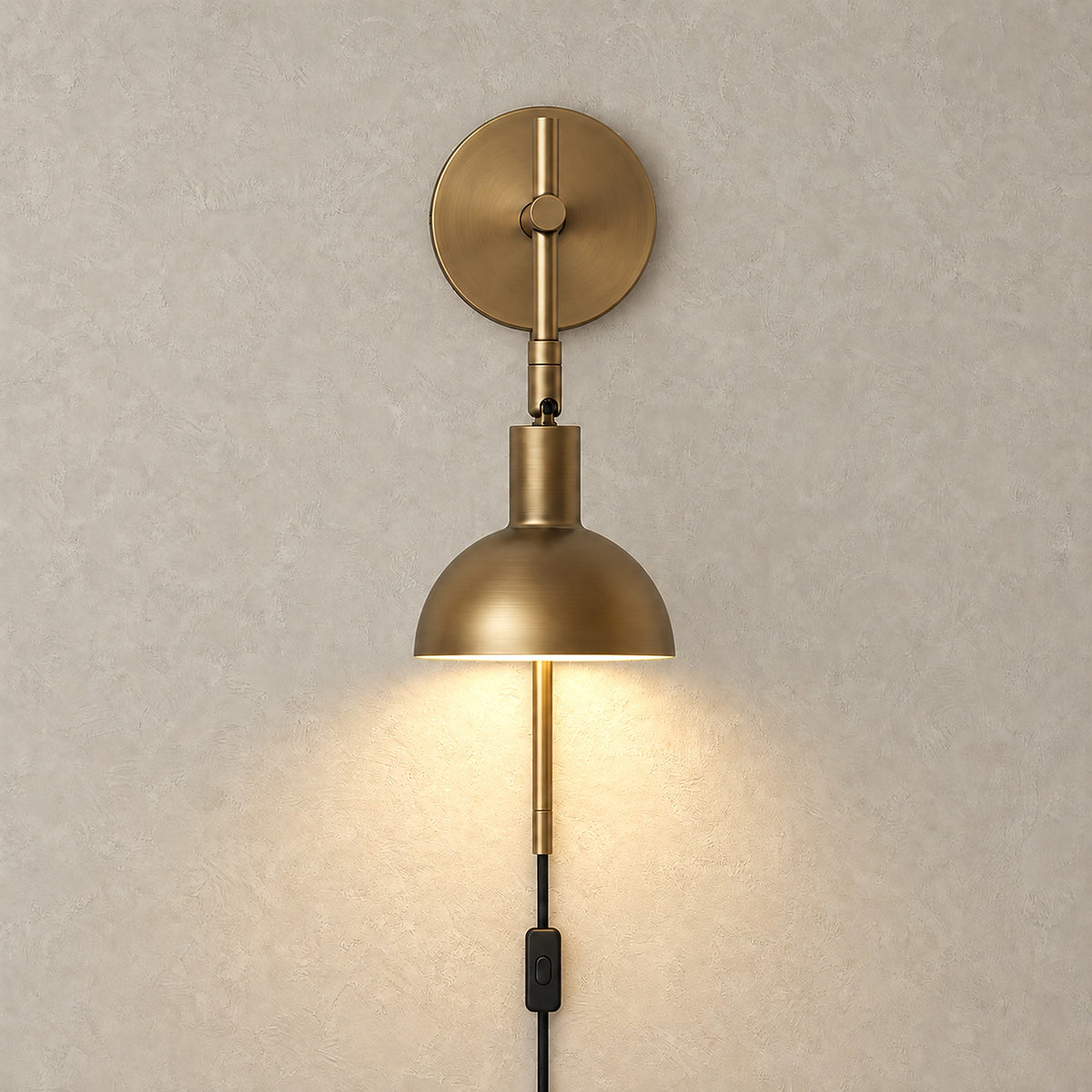 Melcasi plug in led wall sconce with antique brass colored shade glowing with warm white light