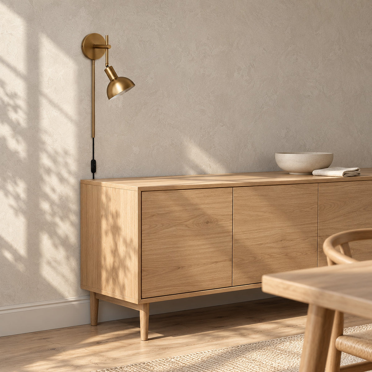 Melcasi led wall sconce with antique brass colored shade unlit above a sideboard in a dining room by day