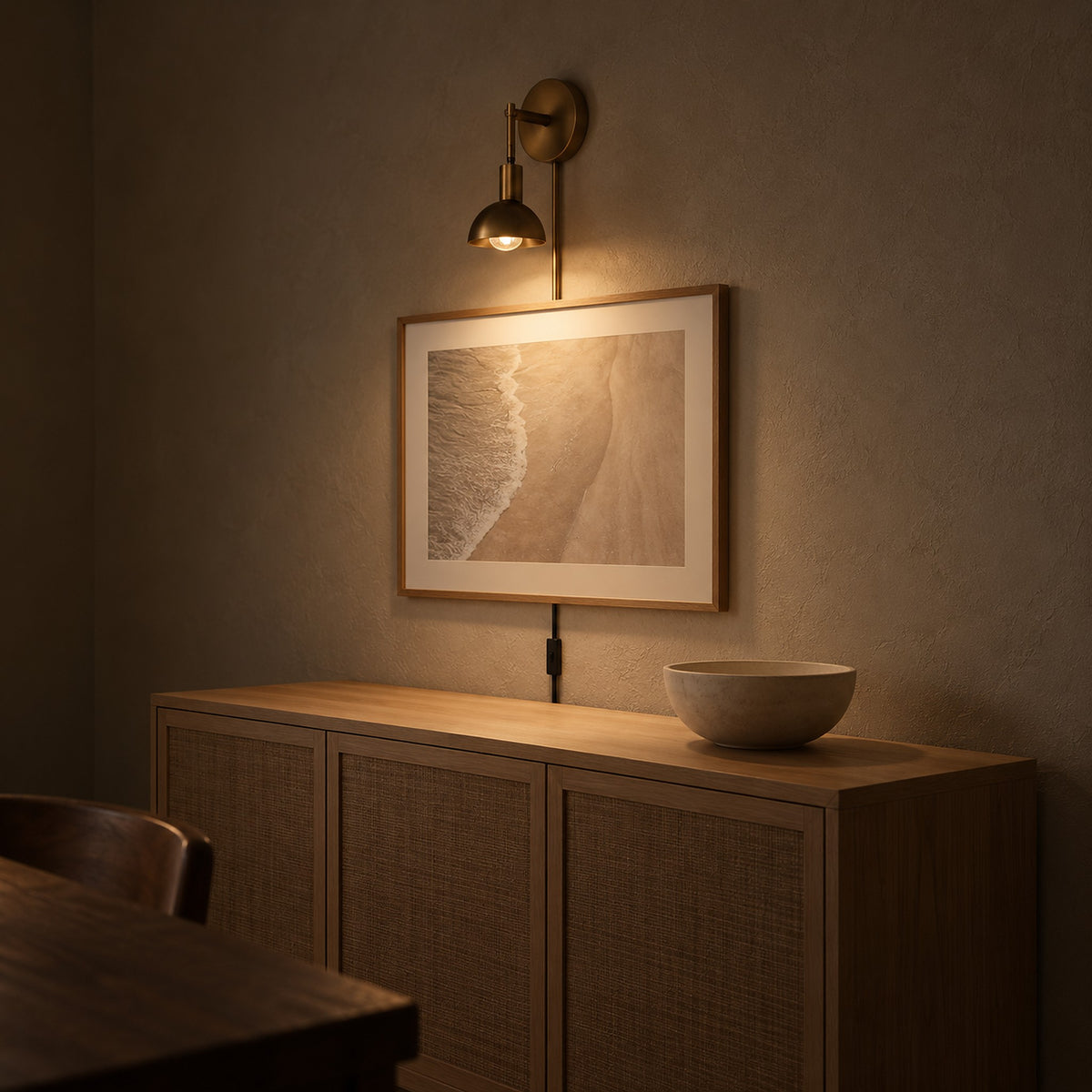 Melcasi led wall sconce with antique brass colored shade lighting artwork in a dining room at night