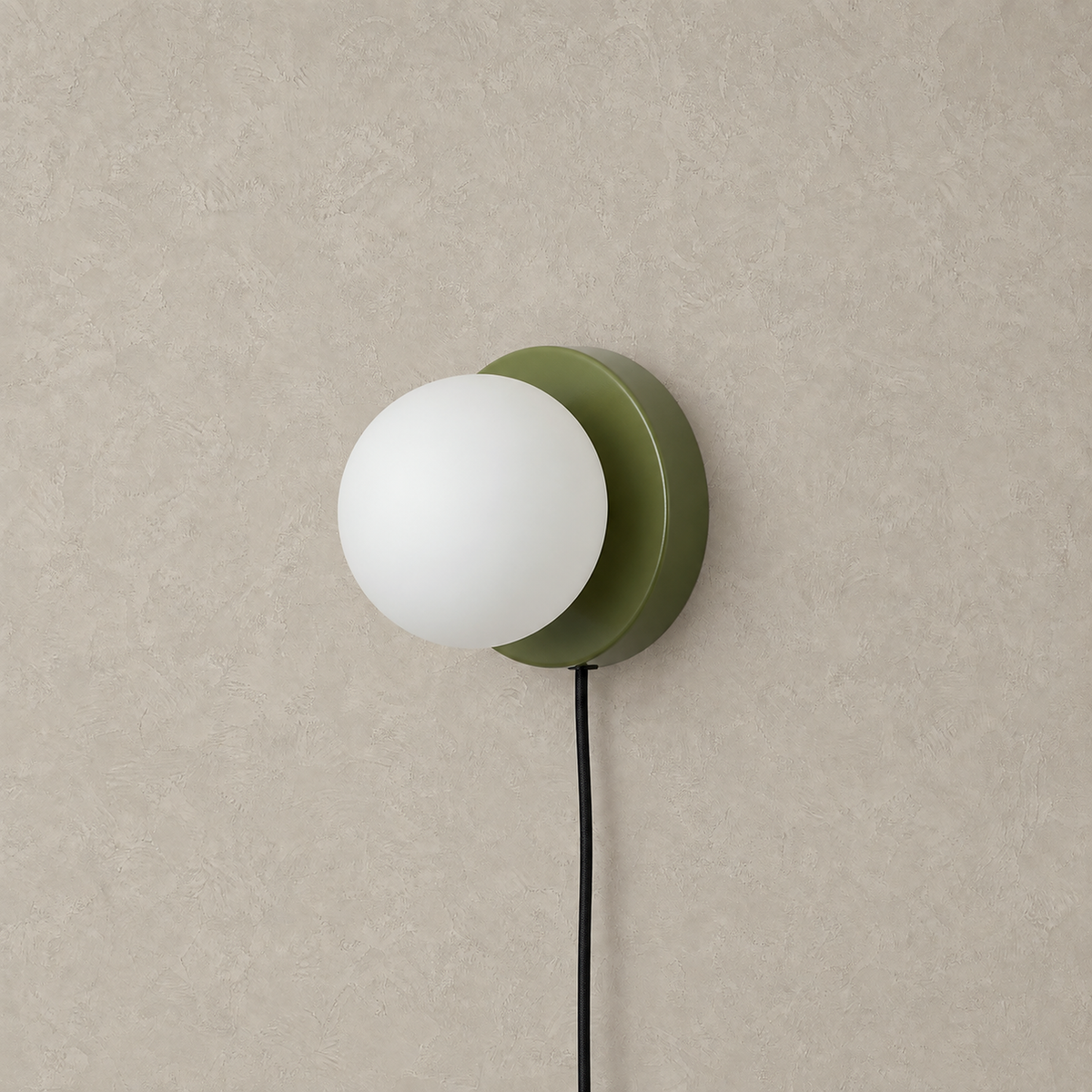Memilora green plug in wall sconce unlit with its round white globe on a studio plate
