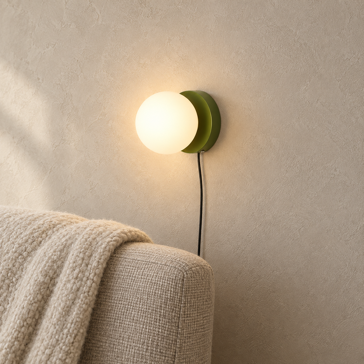 Memilora green wall lamp glowing warm white above an oatmeal chair corner