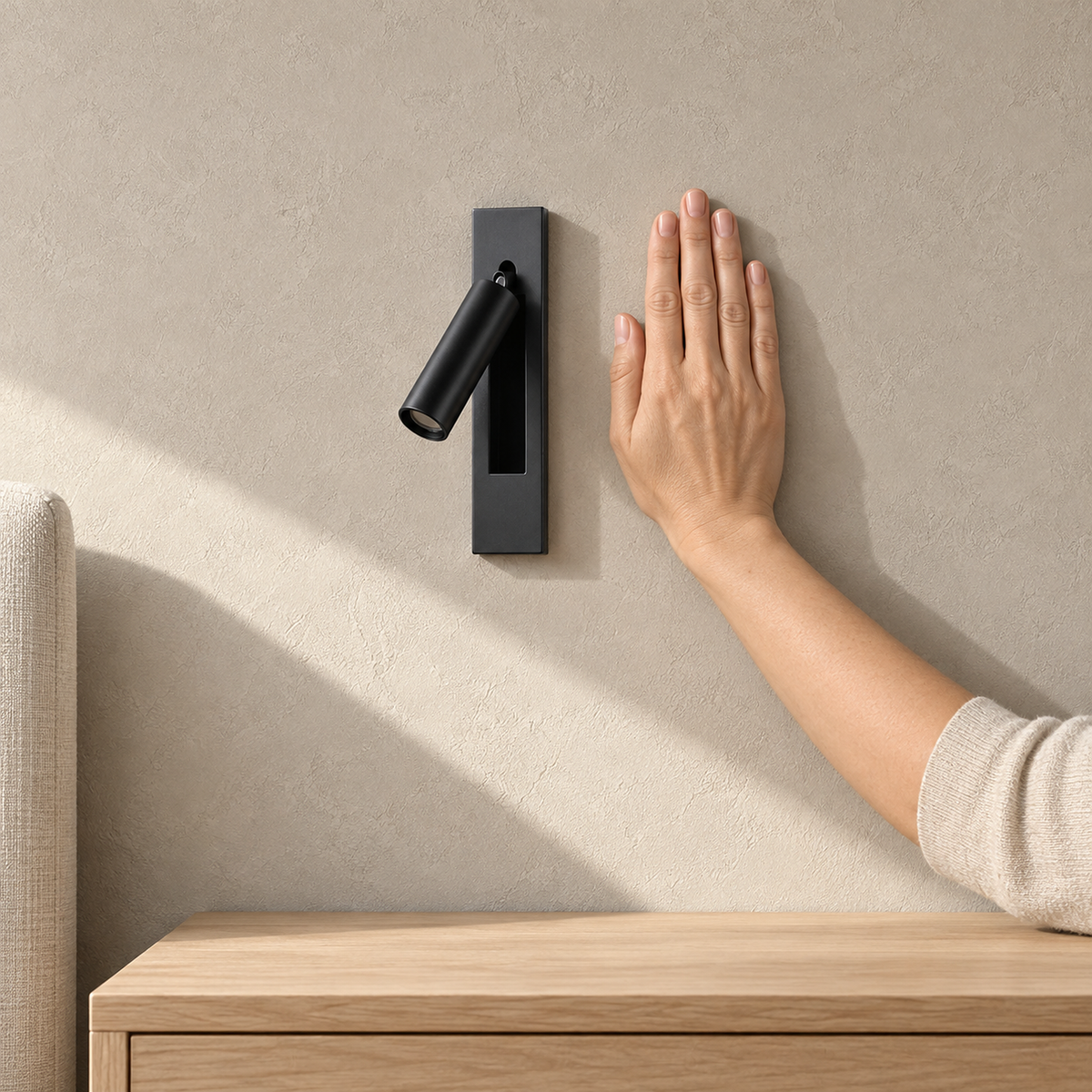 Menaliro black bedside lamp unlit beside a hand above an empty bedside surface in sunlight