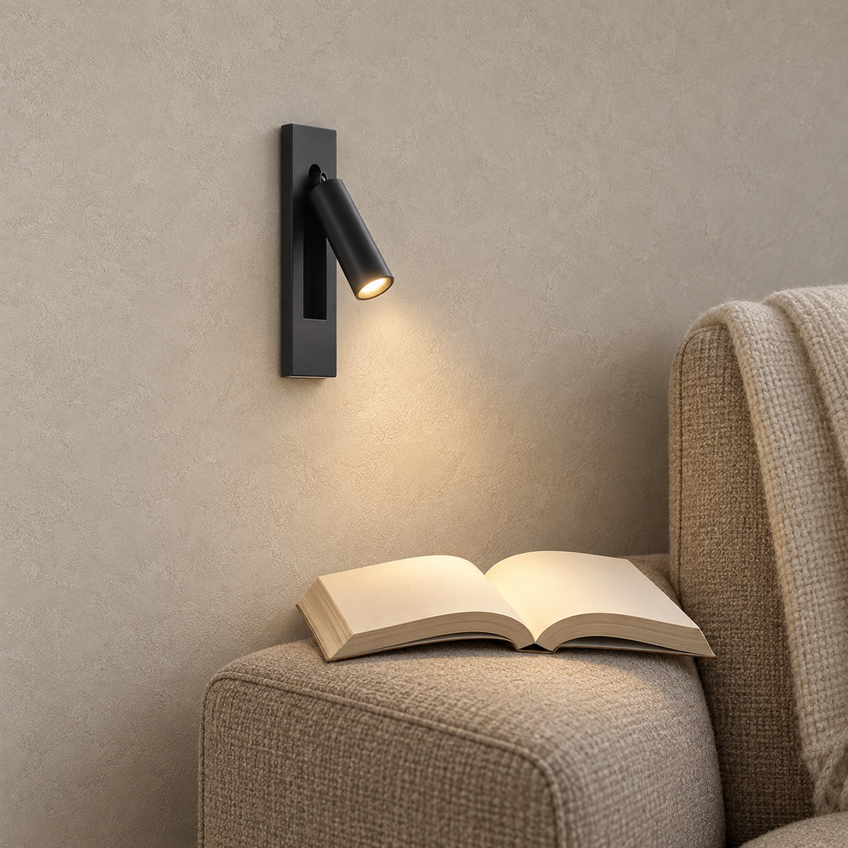 Menaliro black LED wall sconce lit beside an oatmeal reading chair in a library alcove