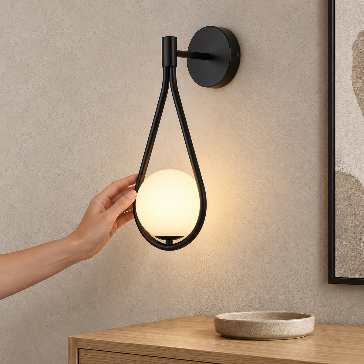 Mesaril black wall sconce lit in an entryway beside a frame on the wall #color_black