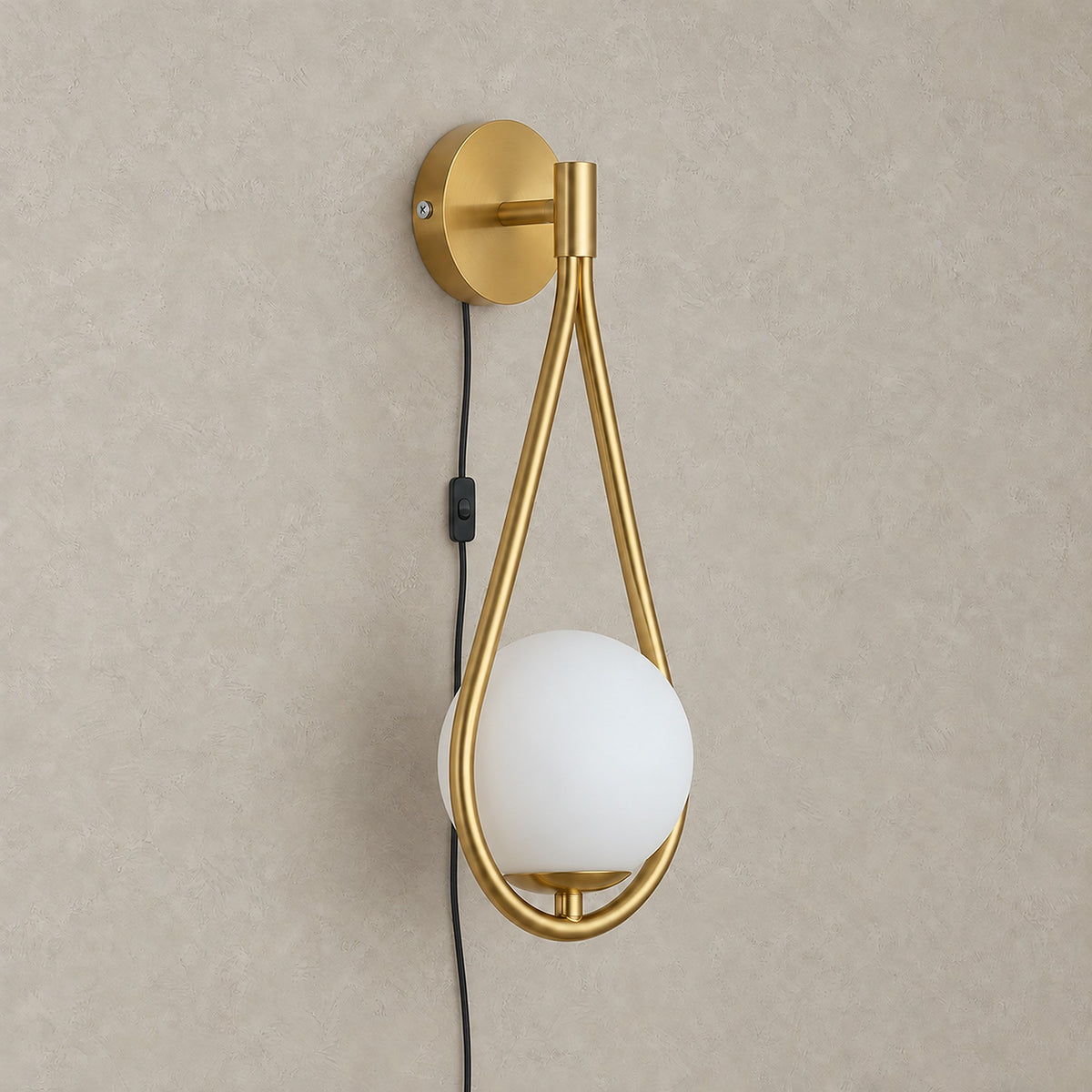 Mesaril gold plug in wall sconce with its black power cord and on/off switch running down the wall