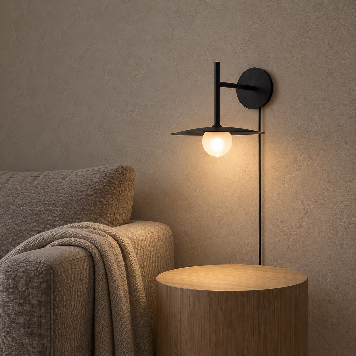 Milvaro black wall sconce giving soft light above a clear den side table #color_black
