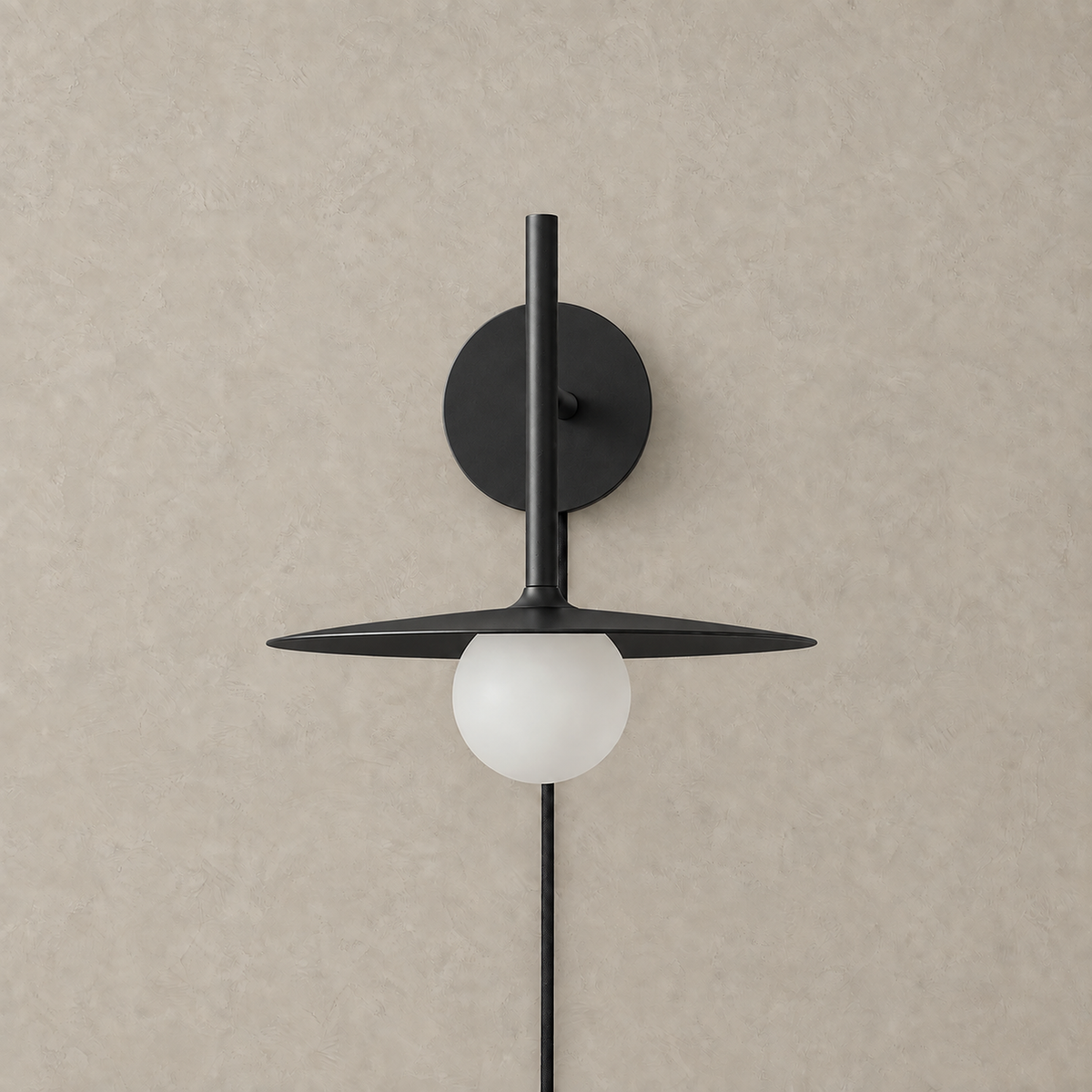 Milvaro black plug in wall sconce unlit against a plain plaster wall showing the globe #color_black