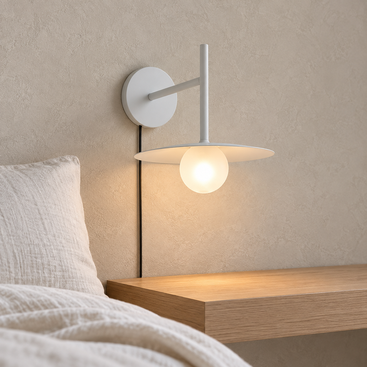Milvaro white wall sconce glowing beside a guest bed above a clear ledge
