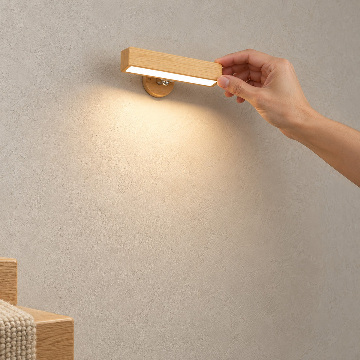 Mirsavel Natural wall sconce casting warm light downward, with a hand touching the wooden bar.