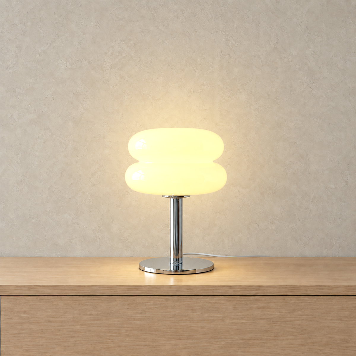 Misolen cream bedside lamp with its rounded glass shade glowing all over