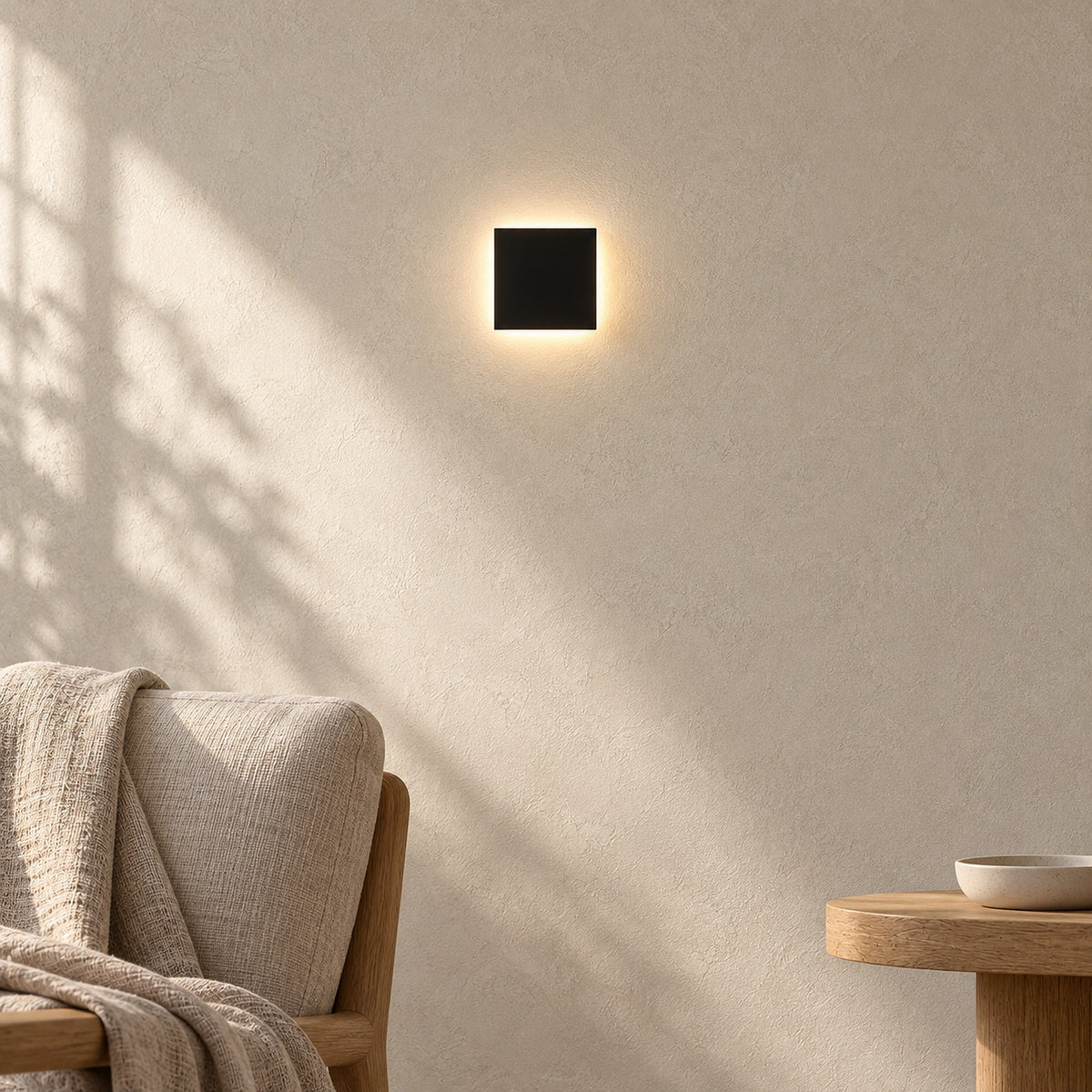 Mivorel black wall light casting a warm halo above a living room chair corner